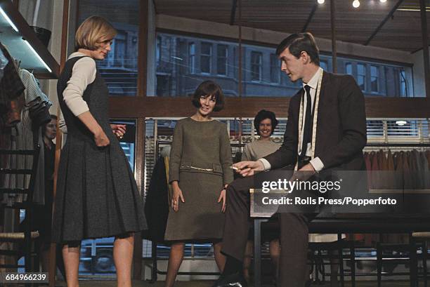 British fashion designer Mary Quant pictured centre with her husband Alexander Plunket Greene as they view a model wearing a pleated pinafore dress...