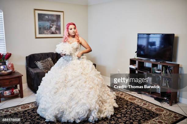 young woman standing in living room dress in quinceanera gown - quinceañera fotografías e imágenes de stock