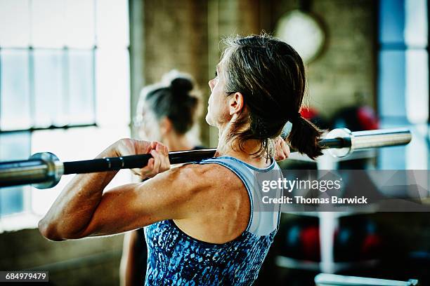 mature woman doing barbell lifts during workout - barbell stock pictures, royalty-free photos & images