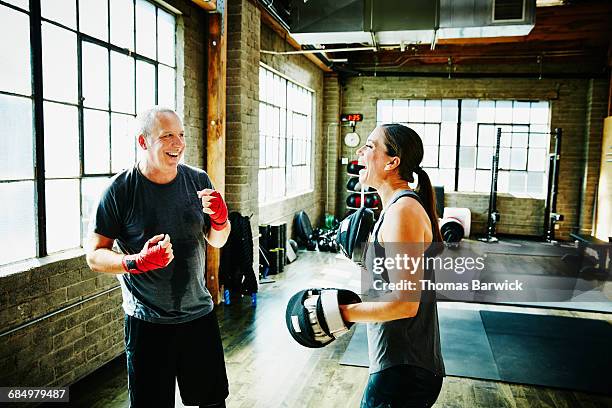 mature athlete and coach laughing during workout - boxing coach stock-fotos und bilder