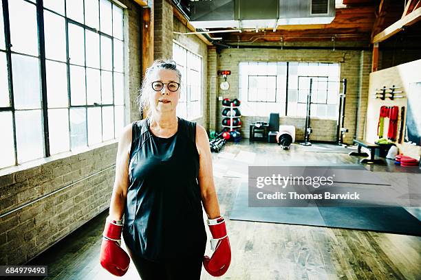 senior woman in gym wearing boxing gloves - boxe femme photos et images de collection