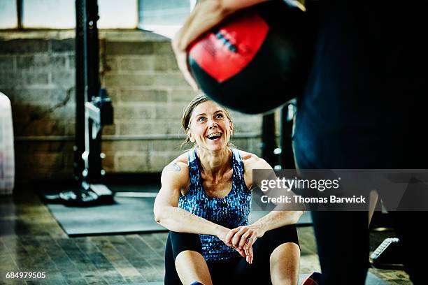 laughing mature woman doing medicine ball crunches - toughness stock-fotos und bilder