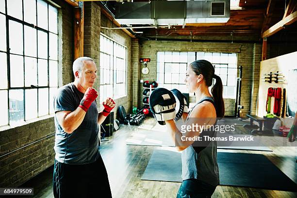 mature male athlete boxing with coach in gym - funny boxing stock-fotos und bilder