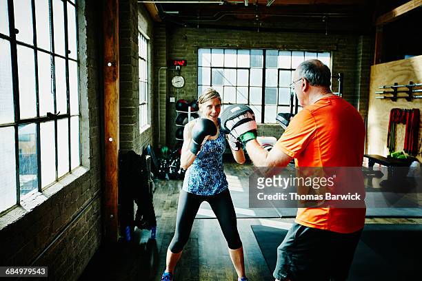 mature woman boxing with workout partner in gym - studying hard stock pictures, royalty-free photos & images