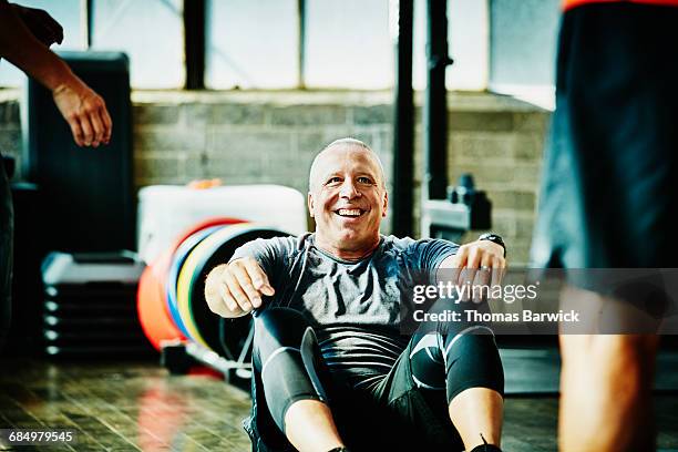 laughing mature man doing crunches during workout - senior woman studio stock-fotos und bilder