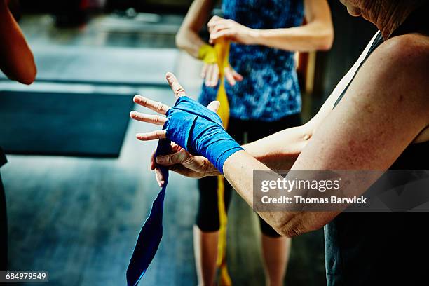 woman wrapping hands before boxing workout - boxen sport stock-fotos und bilder