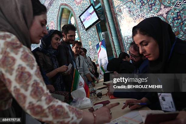 Iranians register before casting their votes for local councils and presidential elections at a polling station in Tehran on May 19, 2017.