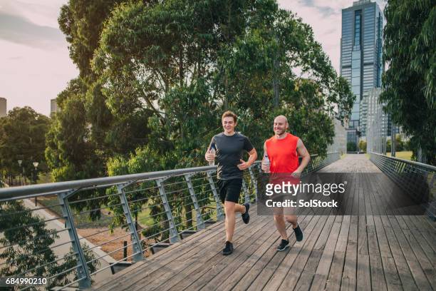 vrienden joggen in het park - man running city stockfoto's en -beelden