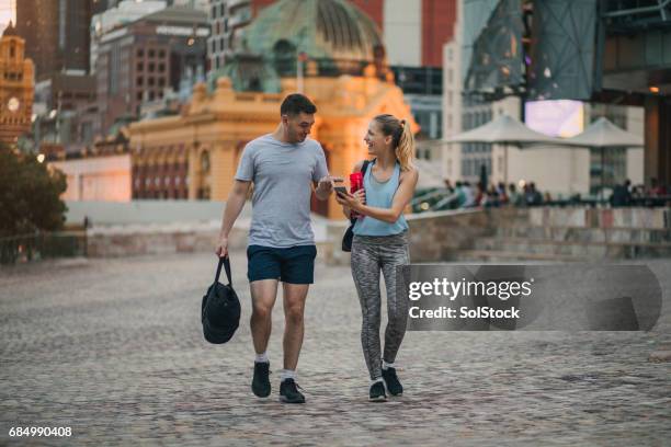 dos amigos vestidos con ropa de athleisure caminando por el centro de la ciudad de melbourne - federation square fotografías e imágenes de stock