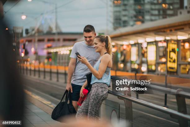 two friends dressed in athleisure clothing waiting for a tram - melbourne australia stock pictures, royalty-free photos & images