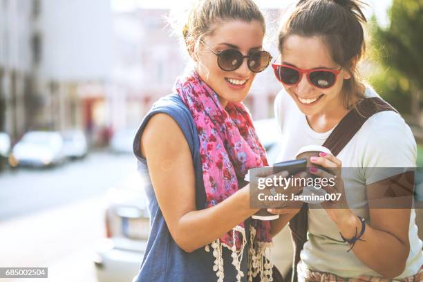 happy female friends reading a text message outdoors - carefree girl stock pictures, royalty-free photos & images