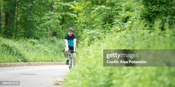 young handsome well trained man riding the sport bicycle in the cunningham park, queens - alex potemkin or krakozawr latino fitness stock pictures, royalty-free photos & images