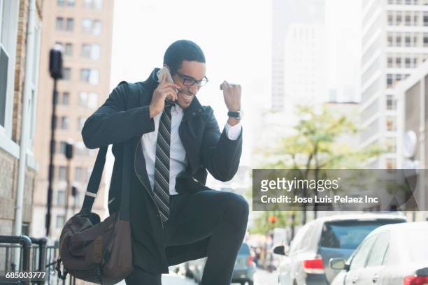 businessman talking on cell phone in city and celebrating - punching the air stock pictures, royalty-free photos & images