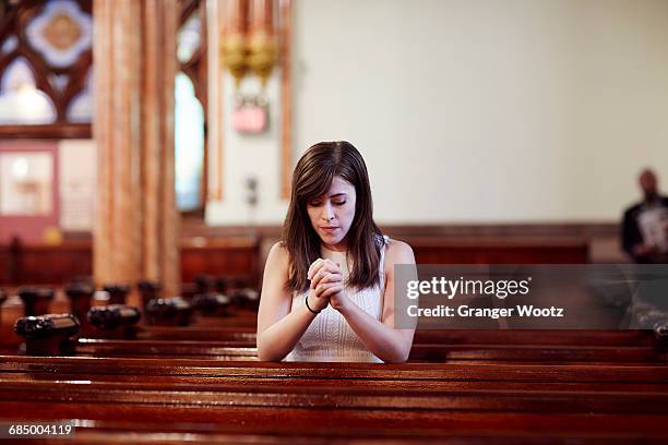 kneeling caucasian woman praying in church pew - church people stock pictures, royalty-free photos & images
