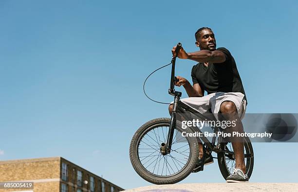 young man on bmx bicycle looking over his shoulder in skatepark - crossfietsen stockfoto's en -beelden