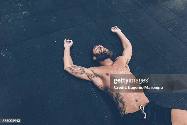 exhausted male cross trainer lying on gym floor - sudan fotografías e imágenes de stock