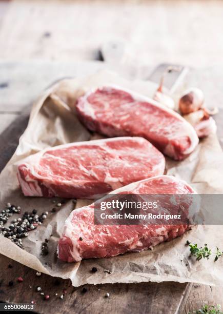 raw steaks on butcher paper with pepper - strip steak stock pictures, royalty-free photos & images