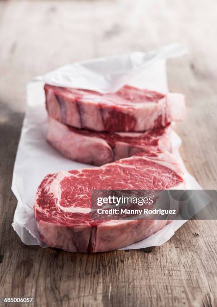 raw rib eye steaks on butcher paper - butcher foto e immagini stock