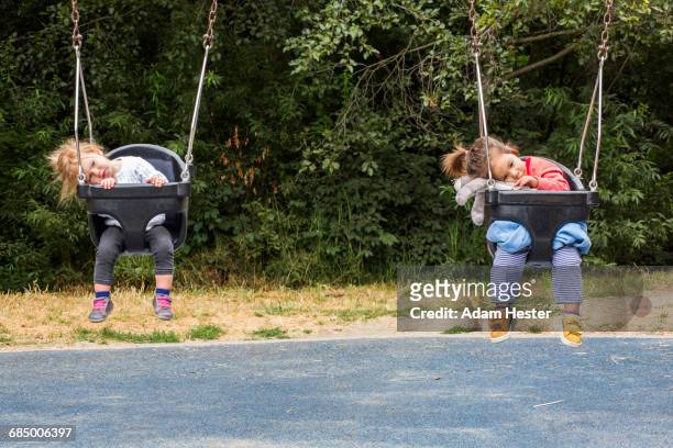 girls sitting in still swings - day 4 stockfoto's en -beelden