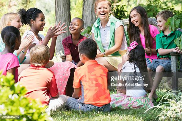 smiling minister mentoring children outdoors - kids interacting in the classroom stock-fotos und bilder
