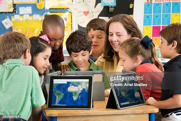 teacher and students using digital tablets in classroom - physical geography stock photos et images de collection