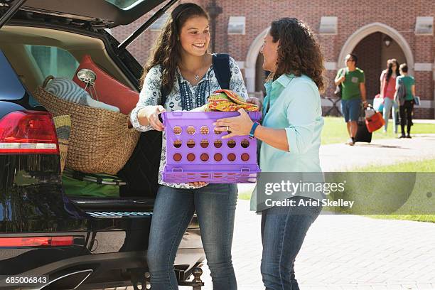 Mother helping daughter unload car at college dormitory