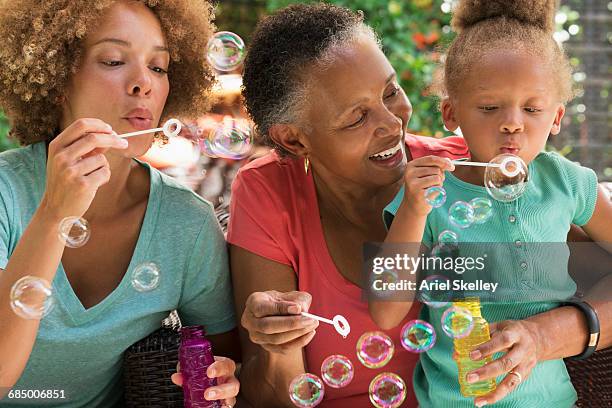 black multi-generation family blowing bubbles outdoors - african american grandparents foto e immagini stock