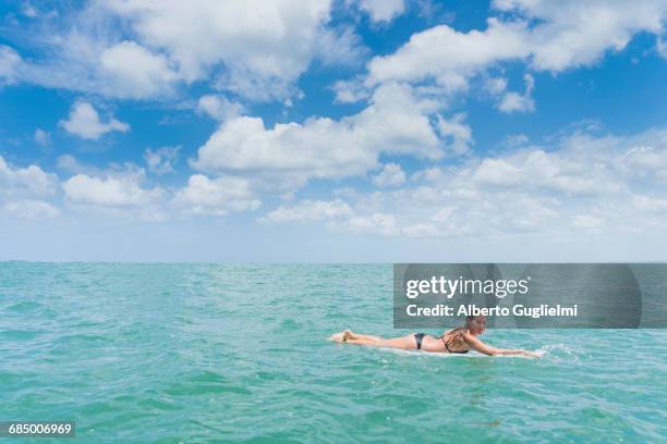 caucasian woman paddling on surfboard in ocean - alberto guglielmi stock pictures, royalty-free photos & images