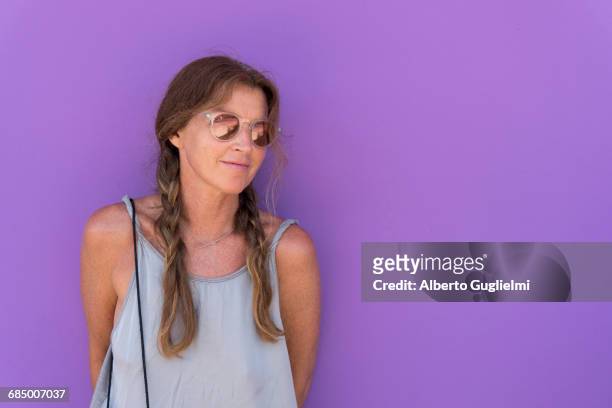 caucasian woman wearing sunglasses leaning on purple wall - alberto guglielmi stock pictures, royalty-free photos & images