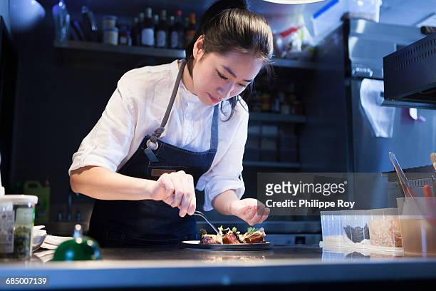chef in commercial kitchen seasoning food - selective focus foto e immagini stock
