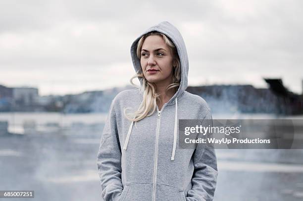 portrait of female runner in hoody on stormy dockside - grey pier stock pictures, royalty-free photos & images