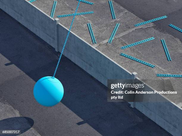 wrecking ball swinging at wall obscuring blue fallen ladders - abrissbirne stock-fotos und bilder