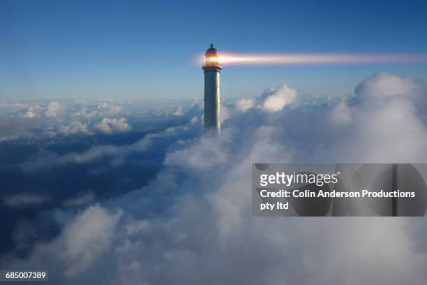 lighthouse beaming above clouds in blue sky - strategy concept photos et images de collection