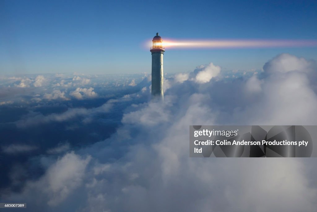 Lighthouse beaming above clouds in blue sky