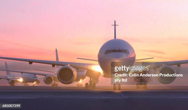 airplanes taxiing on runway at sunset - airport outside stockfoto's en -beelden