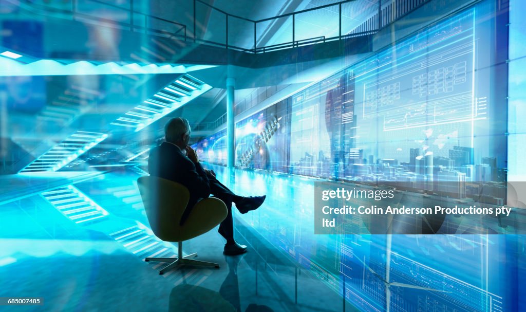 Caucasian businessman sitting in chair in futuristic office