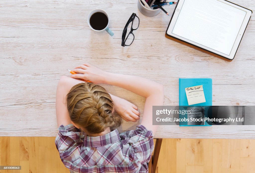 Tired Caucasian woman resting head on wooden table