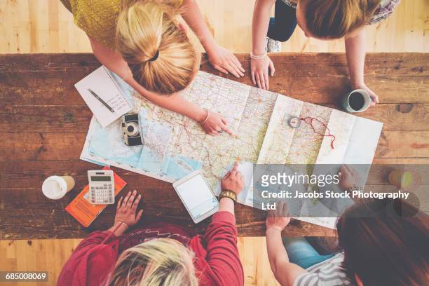 caucasian women planning trip with map on wooden table - journey fotografías e imágenes de stock