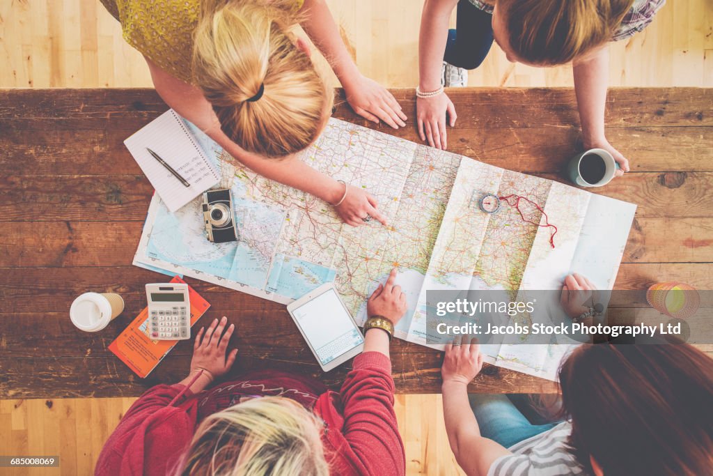 Caucasian women planning trip with map on wooden table