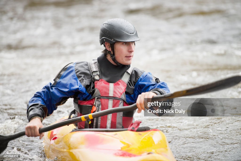 Young male kayaker paddling River Dee rapids
