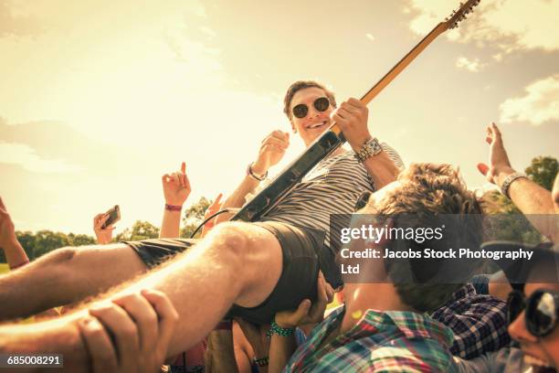 guitarist crowd surfing at concert - stage diving stock-fotos und bilder