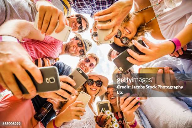 circle of caucasian friends posing for cell phone selfies - medium group of people stock pictures, royalty-free photos & images