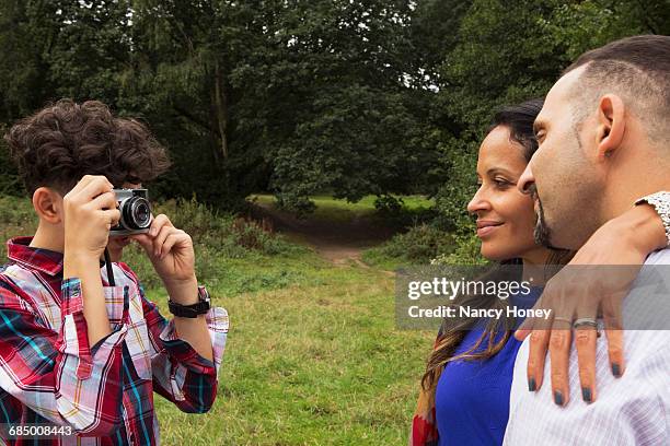 teenage boy photographing parents outdoors, using camera - honey boy fotografías e imágenes de stock