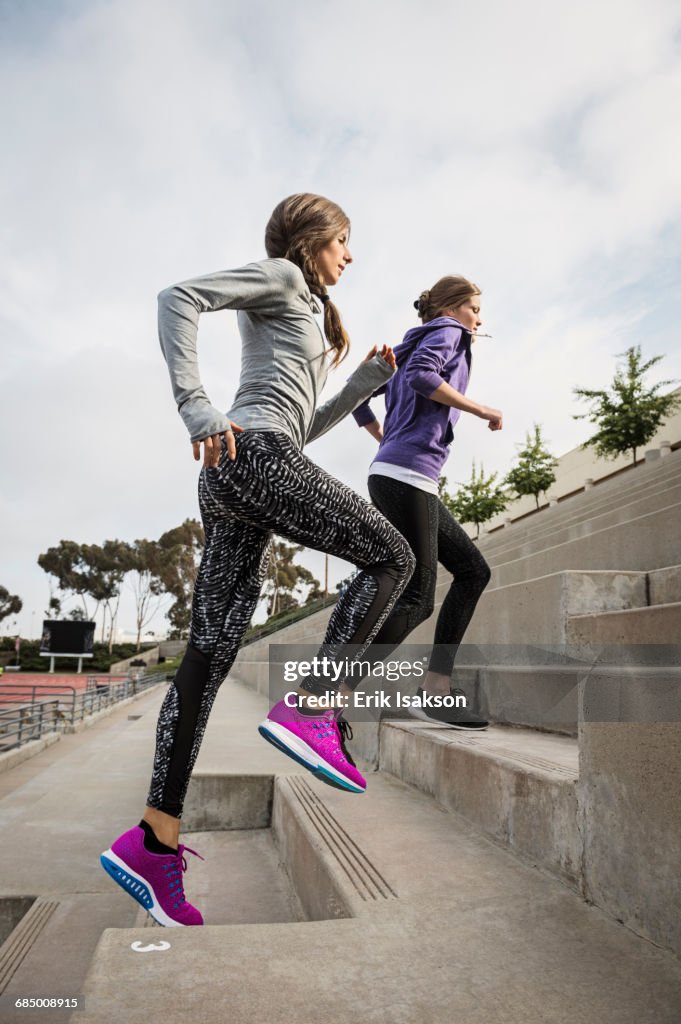 Caucasian women running on stadium staircase