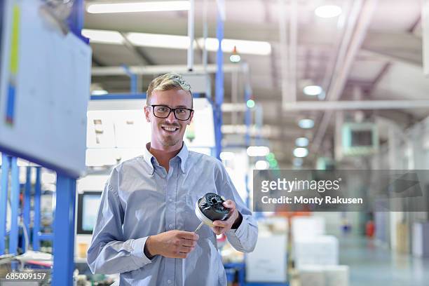 portrait of engineer holding 3d printed exhaust valve actuator in factory - 3d printen factory stockfoto's en -beelden