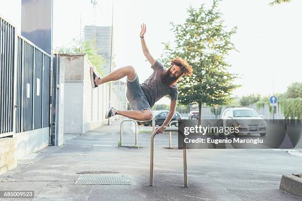 young male hipster kicking up heels on sidewalk - mann freudensprung sonne vorderansicht leger stock-fotos und bilder