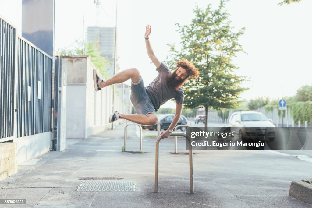 Young male hipster kicking up heels on sidewalk