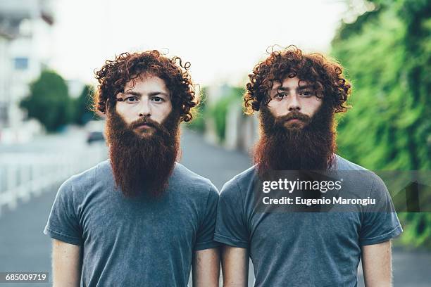 portrait of identical adult male twins with red hair and beards on sidewalk - barba peluria del viso foto e immagini stock