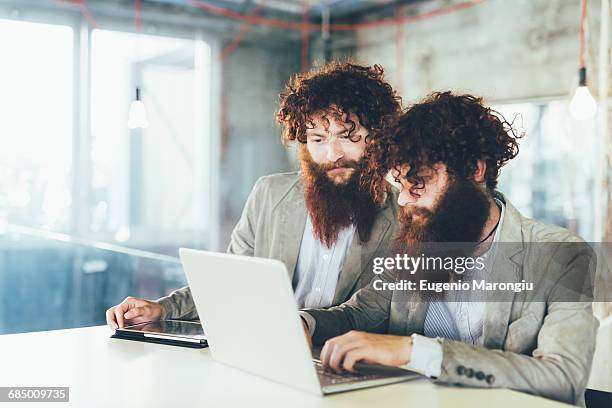 male hipster twins working on laptop at office desk - business owner suit fotografías e imágenes de stock