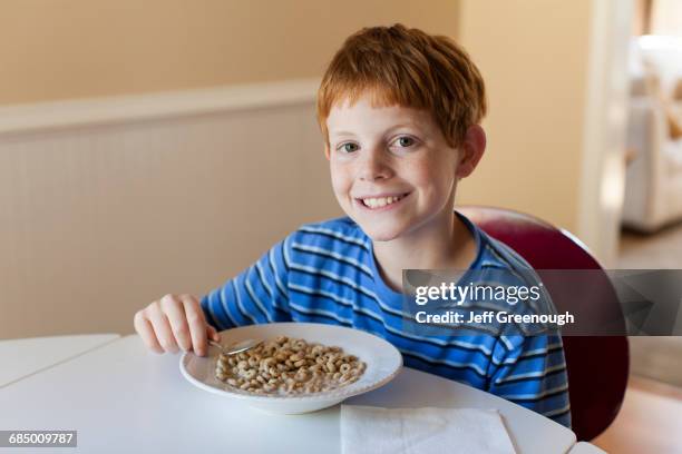 smiling caucasian boy eating cereal for breakfast - boy eating cereal stock pictures, royalty-free photos & images